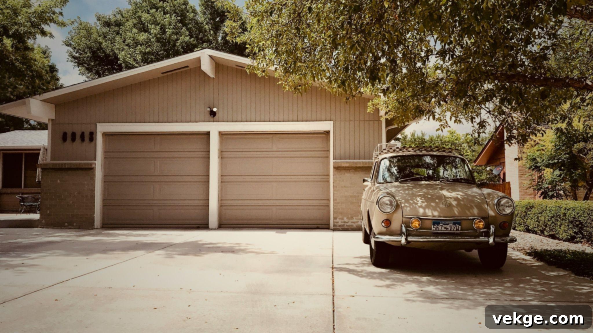 White vehicle parked near a tree and a detached garage.