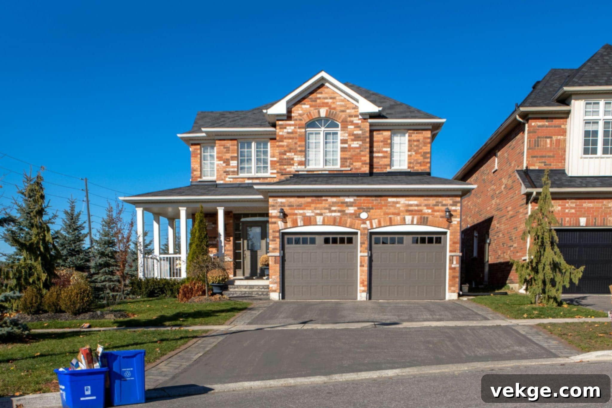 Brown and white concrete house under blue sky during daytime with a well-maintained driveway.