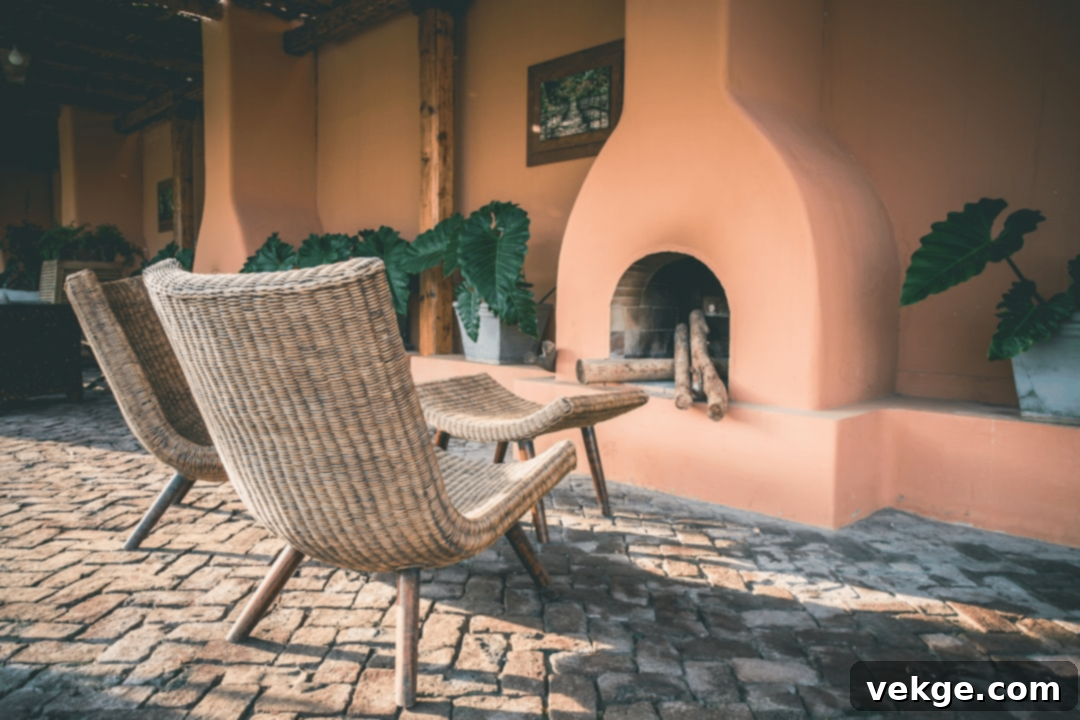 A beautifully designed outdoor patio transformed into an extended living space, featuring comfortable lounge furniture, a warm fire pit, and ambient string lighting, surrounded by lush greenery.