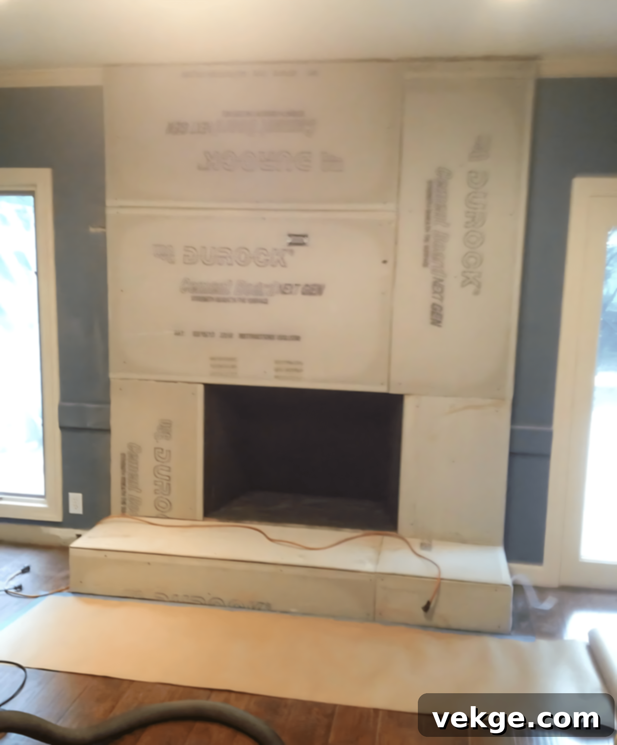 Attaching cement board to a brick fireplace with an electric drill and masonry screws.