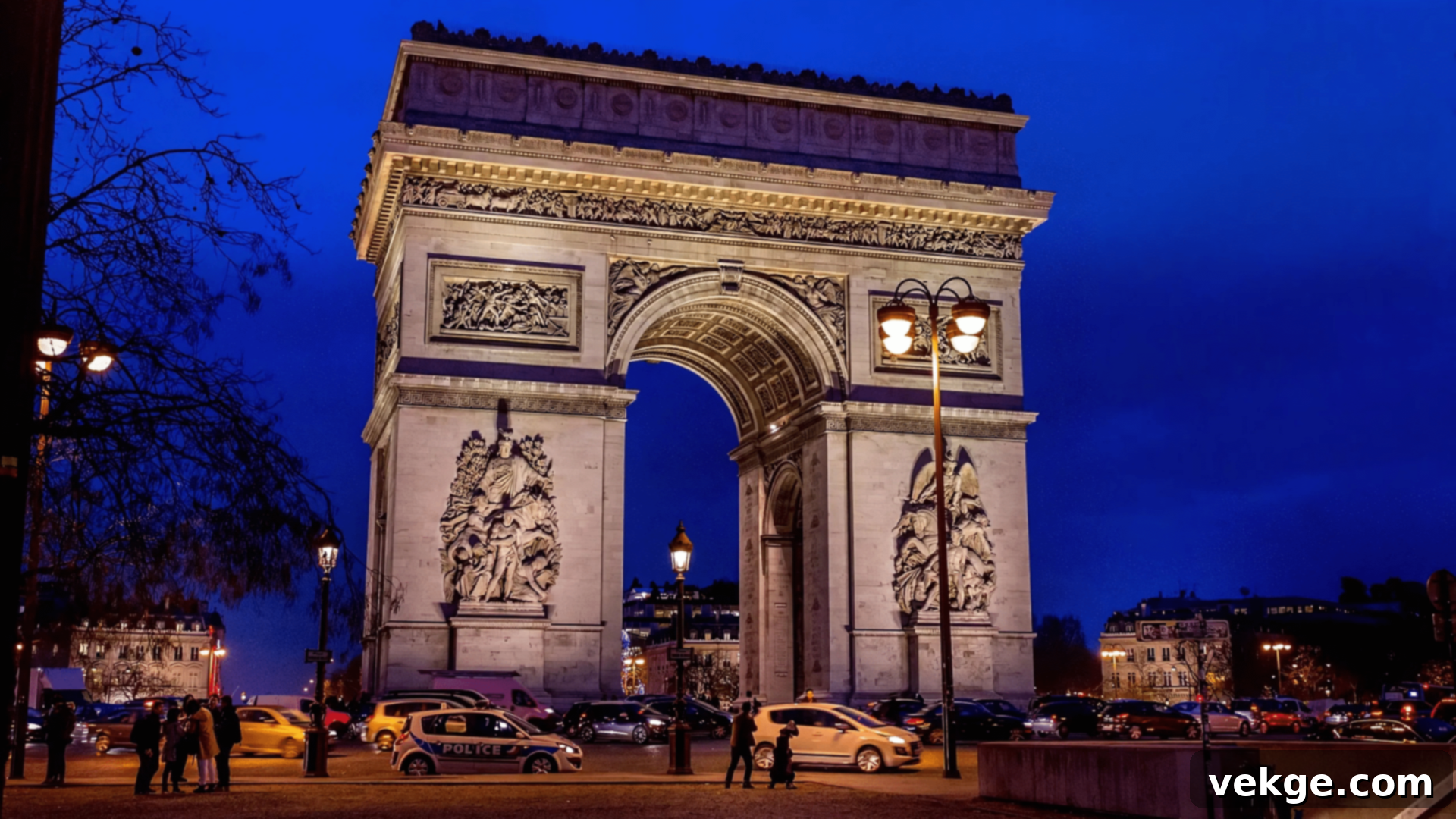 The Arc de Triomphe stands majestically at the center of a bustling Parisian roundabout.