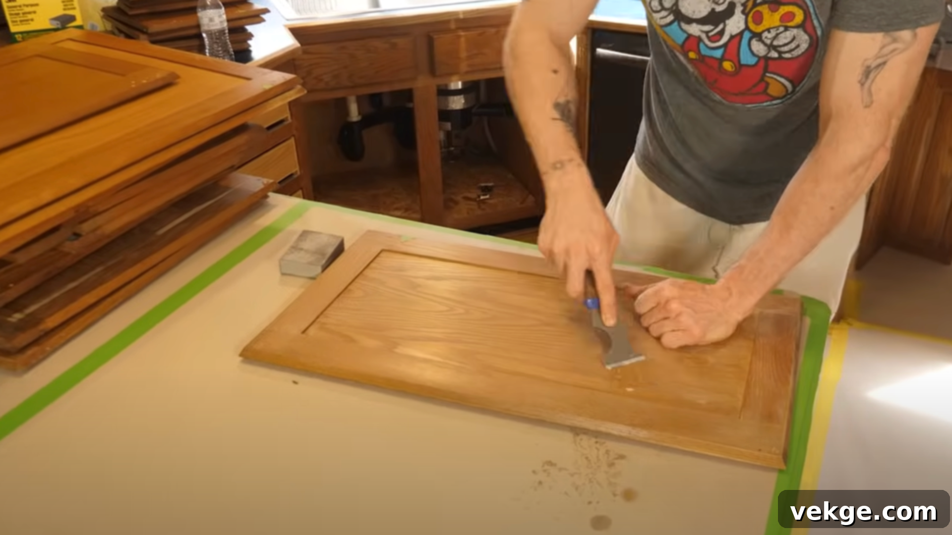 Close-up of a person cleaning a wooden cabinet door with a sponge, preparing it for painting