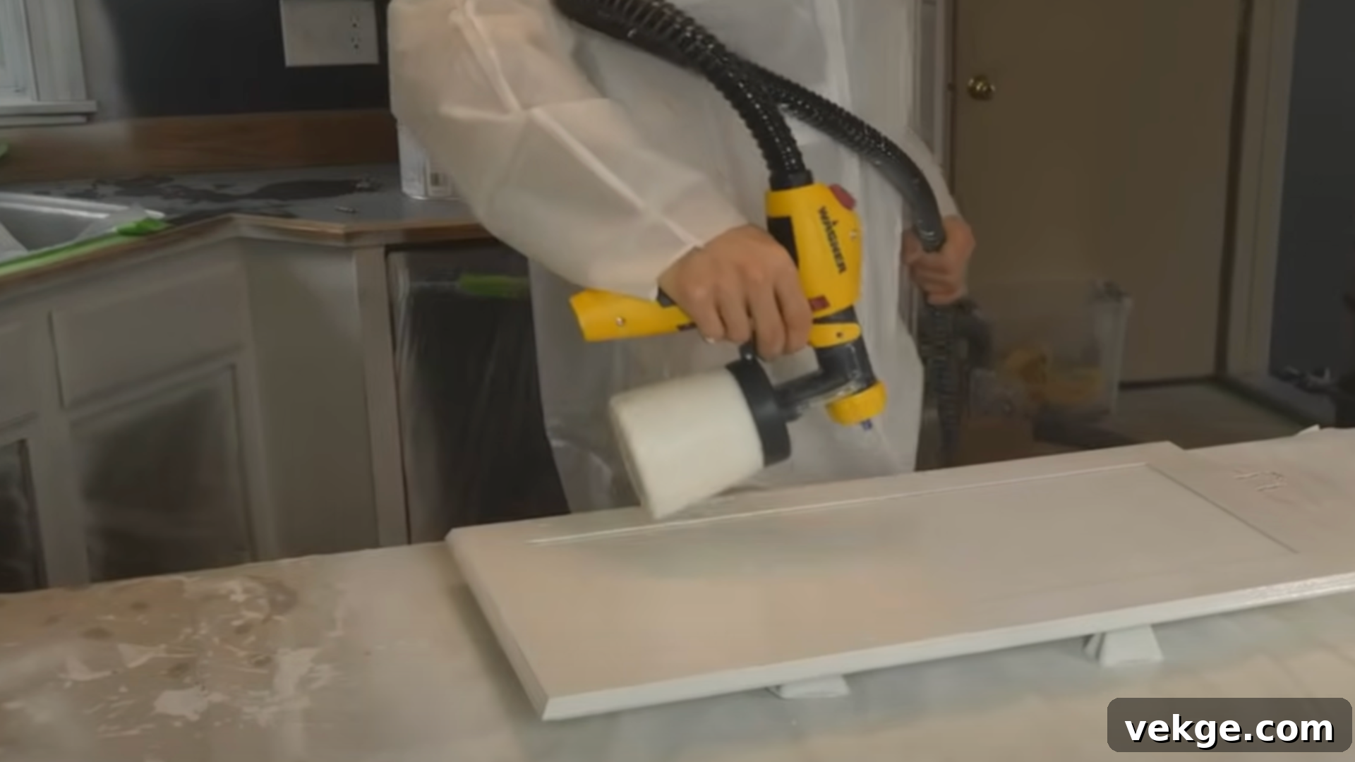 Close-up of a hand painting a kitchen cabinet door with a smooth, even stroke