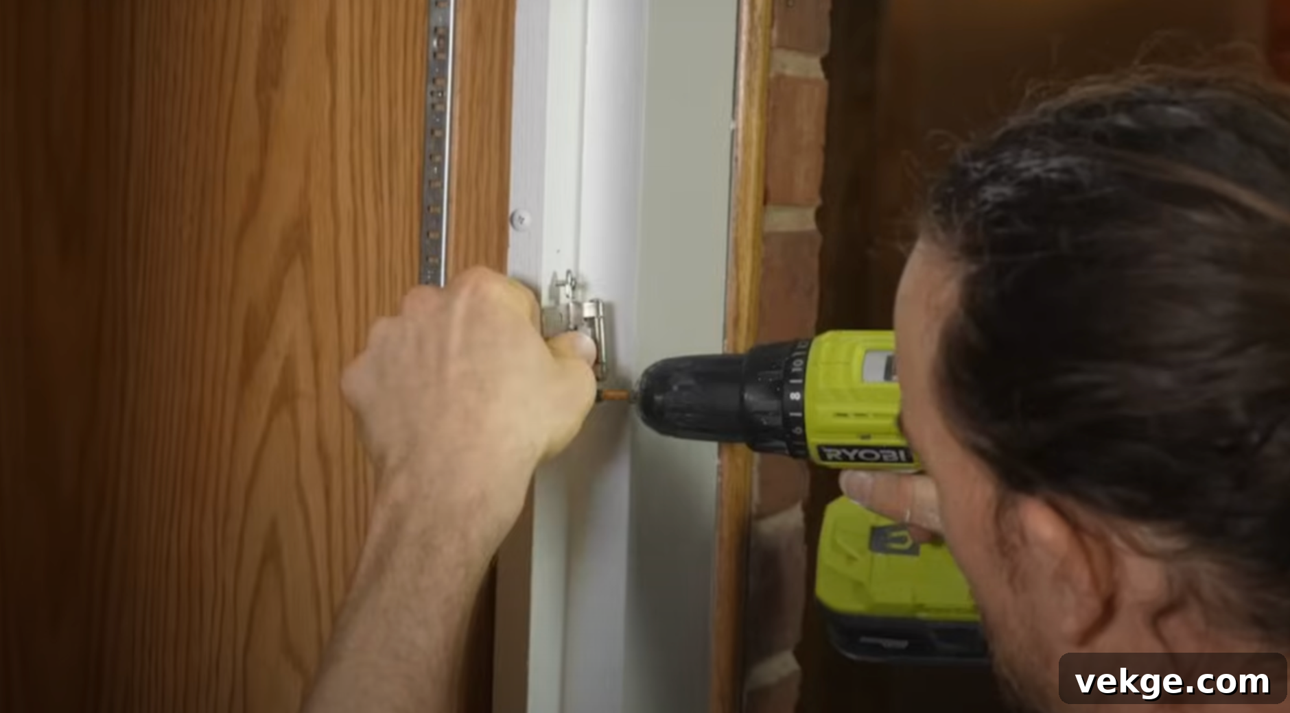 Close-up of a hand installing a modern pull handle on a newly painted kitchen cabinet door