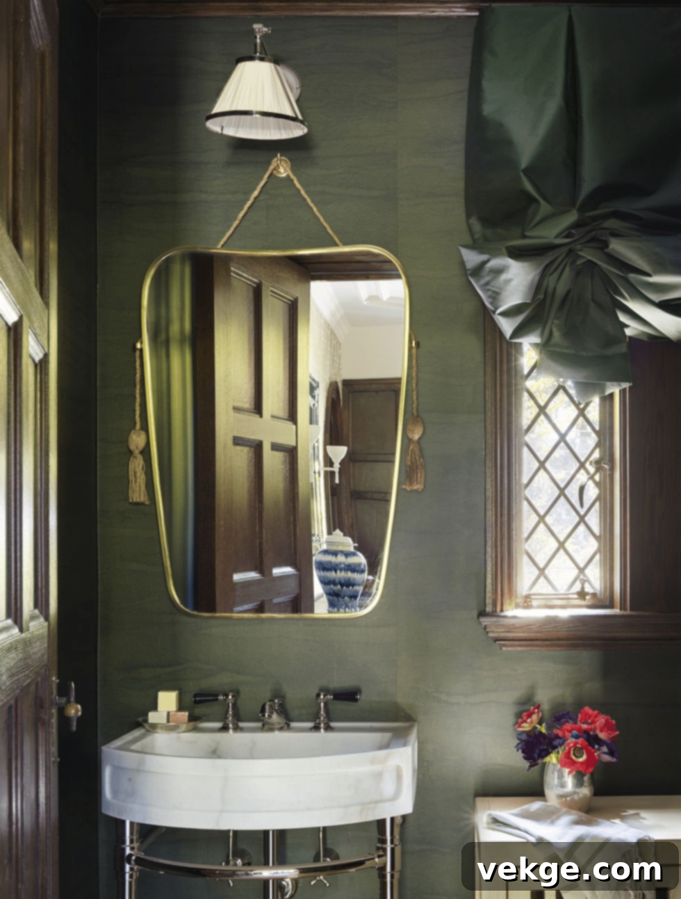 Bathroom layered in rich pops of emerald green with a polished washstand and art-deco mirror