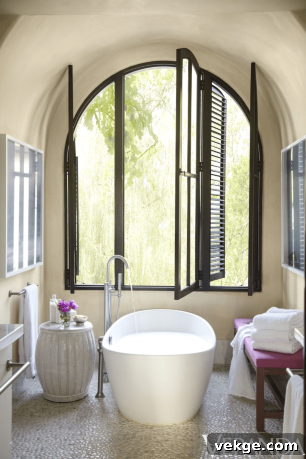 Coastal-look bathroom with stone flooring, large tub, matte fittings, and a bench with cushion
