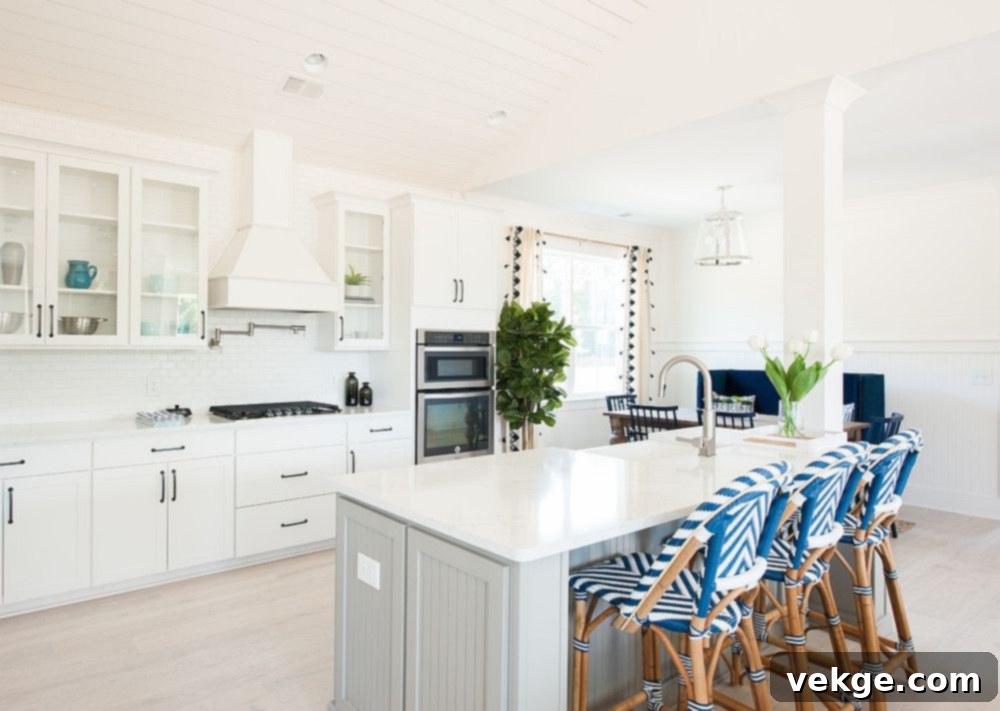 Bar chairs bring pattern to the all white kitchen with relaxing beach style
