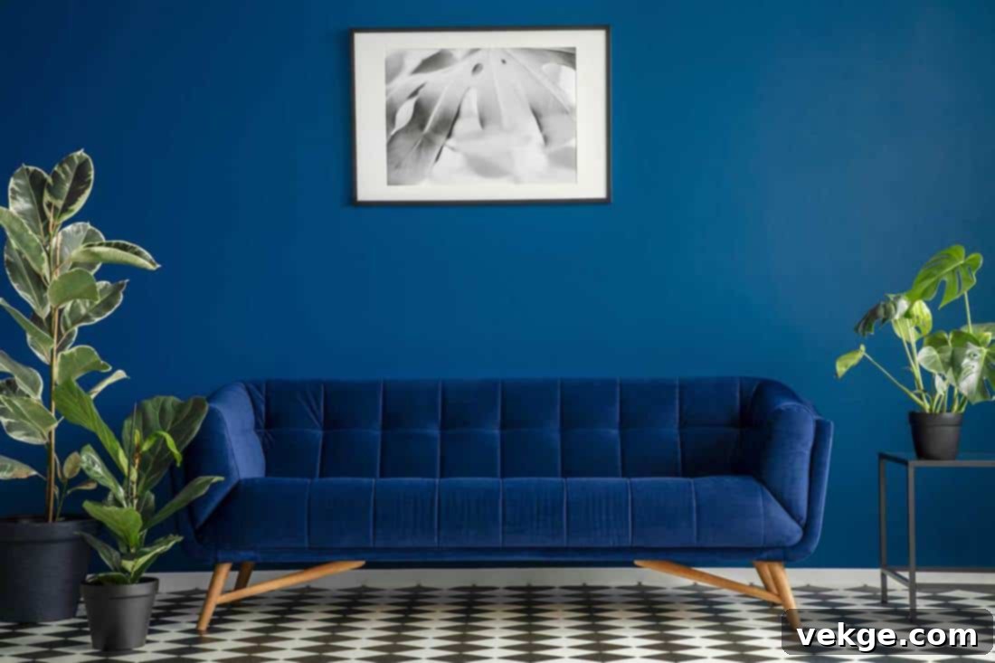 Luxurious dark blue plush couch surrounded by green plants standing on a chessboard floor in a living room interior