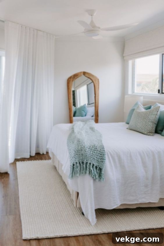 Bedroom with sheer white curtains, creating a bright and airy coastal ambiance