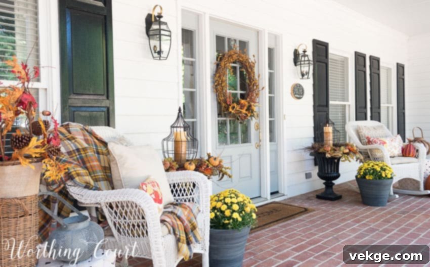 Farmhouse style front porch with fall decor, rocking chairs, and urns