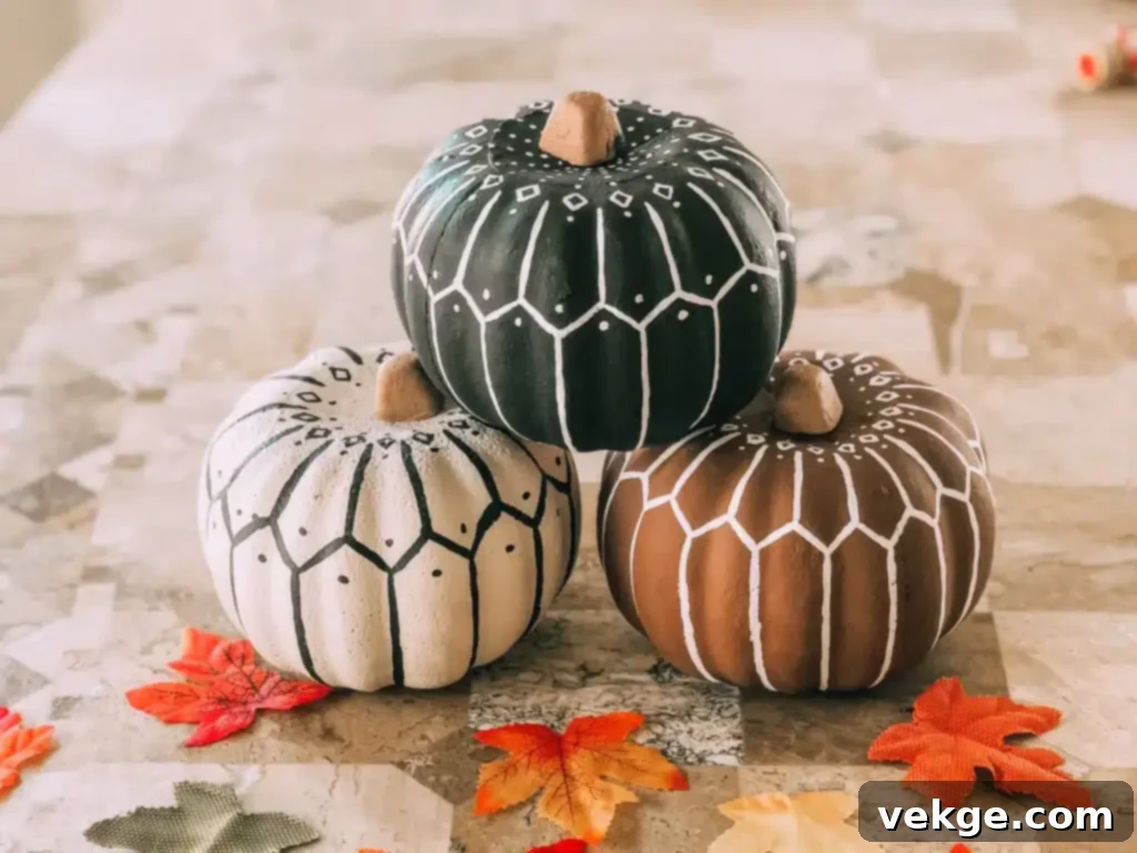 Three knitted or decorated pumpkins sitting on a table with leaves