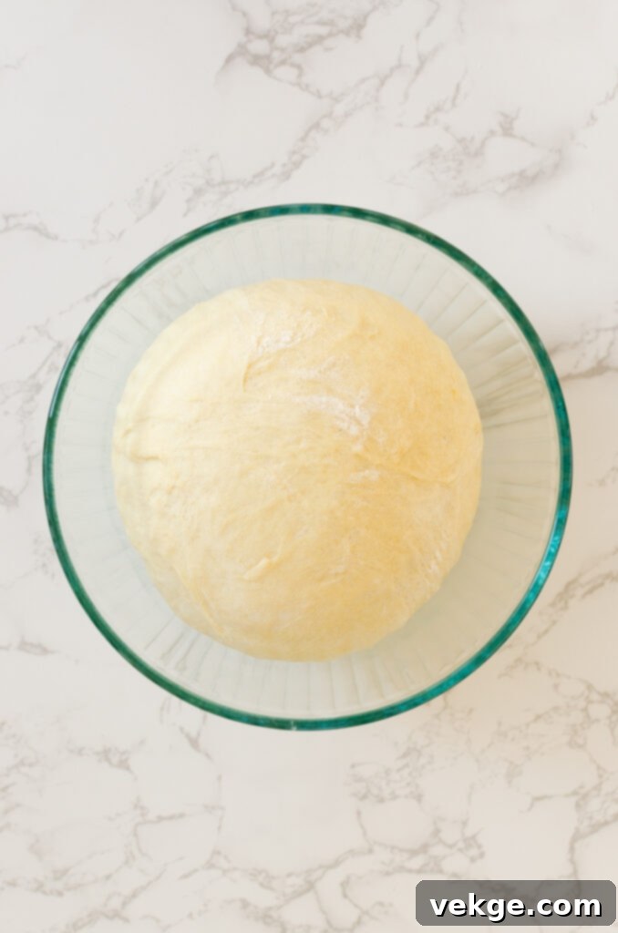 Sweet Orange Swirls 5 Orange roll dough being rolled out into a large rectangle on a floured surface.