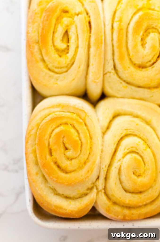 Sweet Orange Swirls 7 Freshly baked orange rolls, golden brown and puffed, cooling on a rack before frosting.