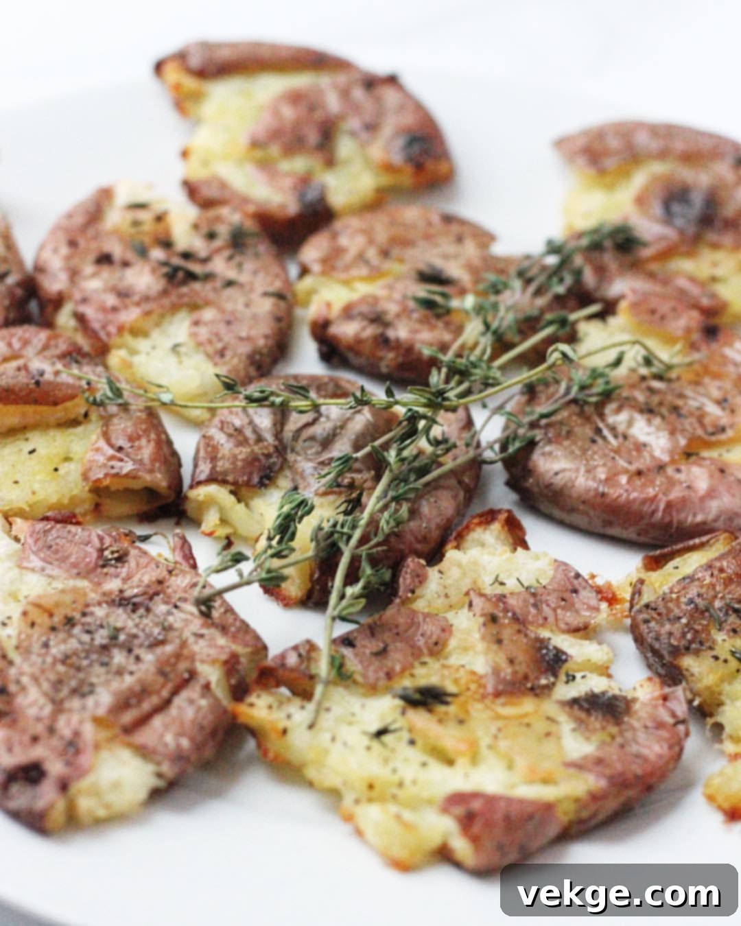 An overhead view of a baking sheet filled with smashed red potatoes, ready for roasting.