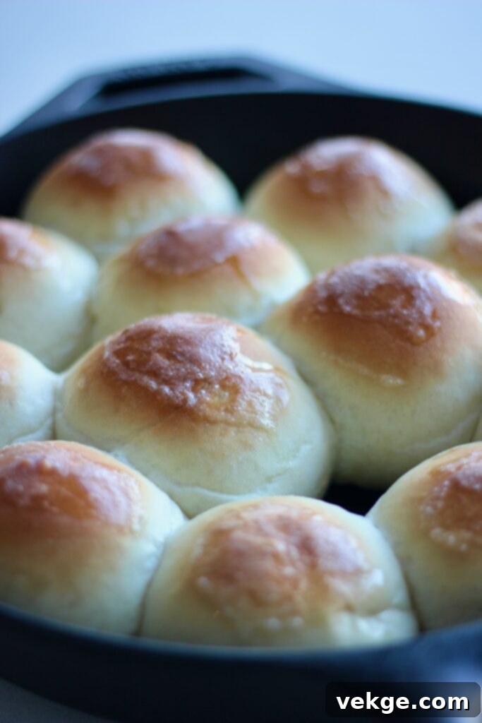 Freshly baked dinner rolls being brushed with melted butter.