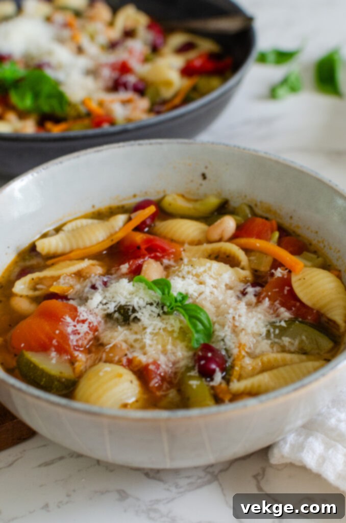 Effortless Instant Pot Minestrone 8 A bowl of Instant Pot Minestrone Soup served alongside slices of crusty bread and a small bowl of grated Parmesan cheese.