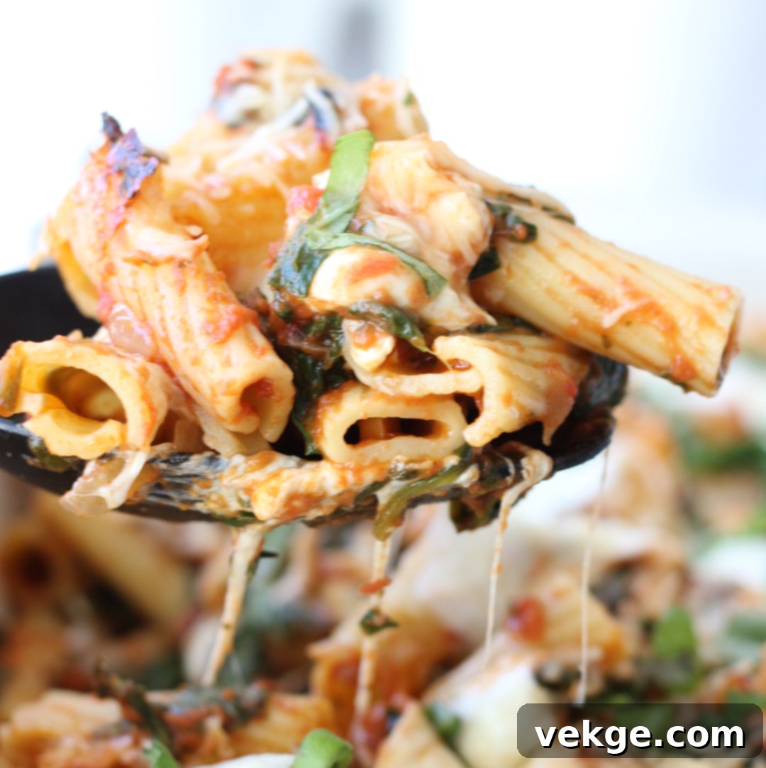 Vibrant Spinach and Fresh Mozzarella Rigatoni 3 Close-up of a portion of baked rigatoni, showcasing the melted cheese, rigatoni tubes, and spinach