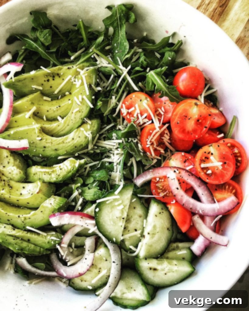 Fresh & Zesty Arugula Salad 2 A vibrant arugula salad with parmesan, cucumber, tomato, red onion, and avocado.