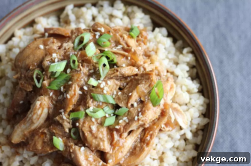 Golden Honey Sesame Chicken 4 A vibrant close-up image of a bowl of Honey Sesame Chicken with a side of white rice and a sprinkle of green onions and sesame seeds.