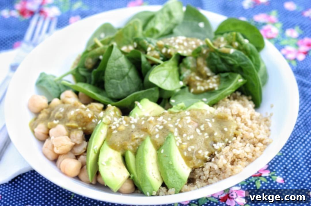 Close-up of a Coconut Curry Buddha Bowl, highlighting the texture of the creamy sauce, fluffy quinoa, golden roasted chickpeas, and fresh green spinach, ready to be enjoyed.