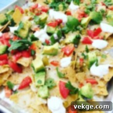 Close-up of golden, crispy tortilla chips loaded with melted cheese and vibrant toppings.