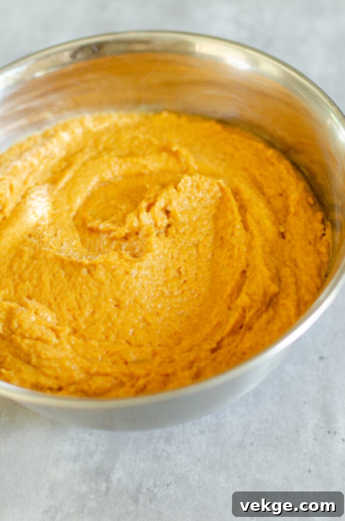 Mixing wet ingredients for pumpkin chocolate chip muffins in a large bowl.