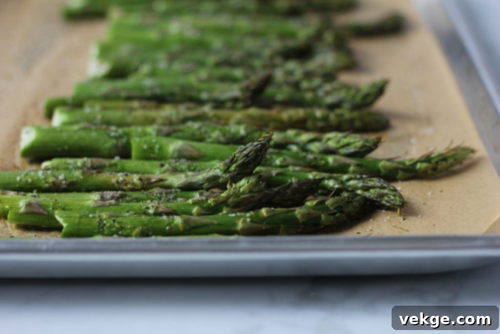 Asparagus on a baking sheet, drizzled with oil and seasonings