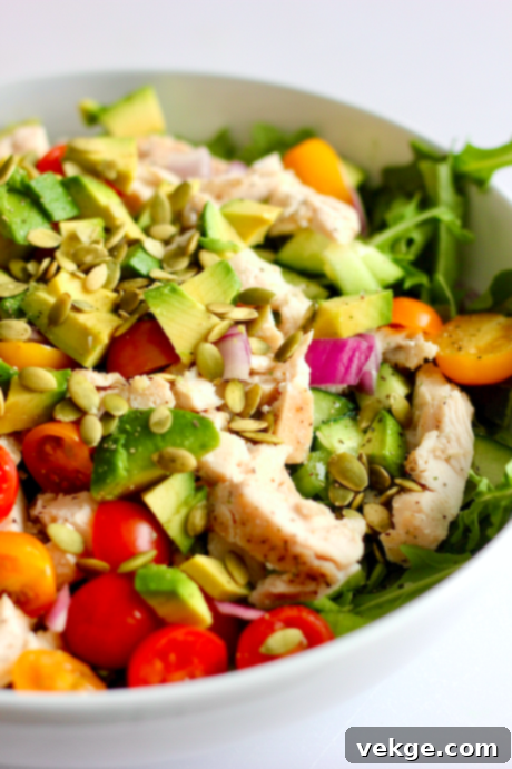 A close-up of a vibrant homemade salad, showcasing fresh ingredients like mixed greens, chicken, and avocado.