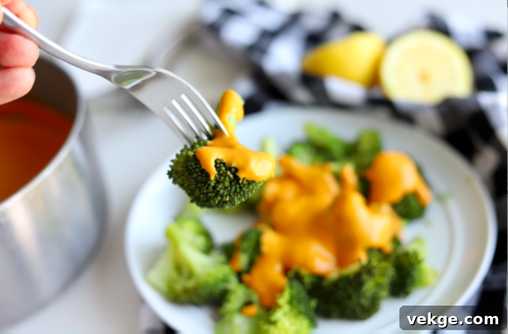 Creamy Vegan Cheese Sauce 2 Creamy vegan cheese sauce drizzled over fresh steamed vegetables, showcasing its rich texture and vibrant color.