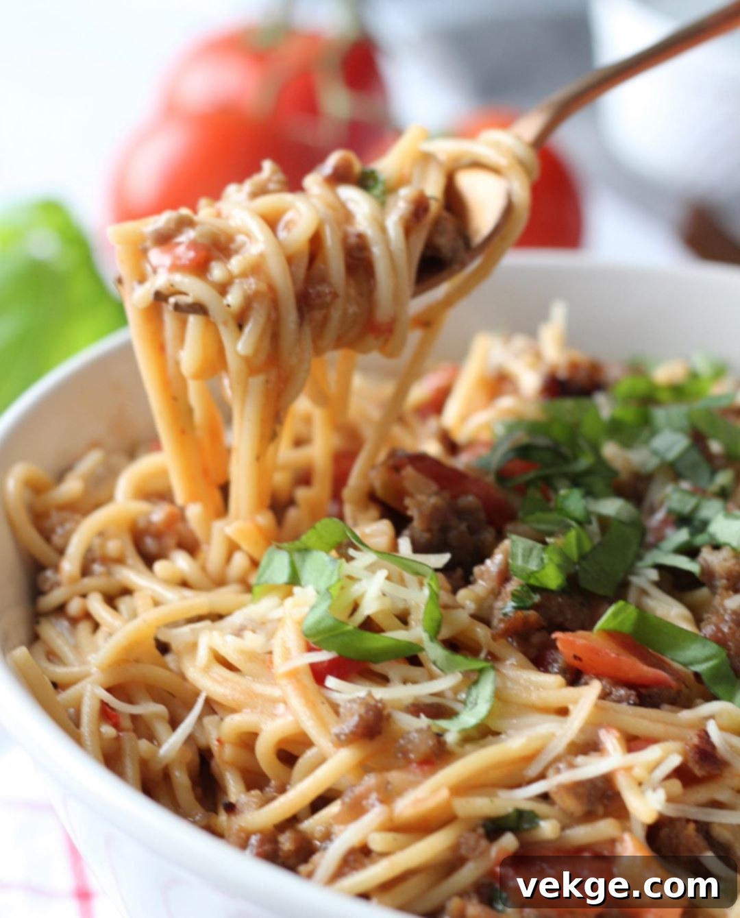 A vibrant close-up of Pasta with Sausage, Fire-Roasted Tomatoes, and Basil, garnished with fresh basil leaves and grated Parmesan cheese, ready to be served.