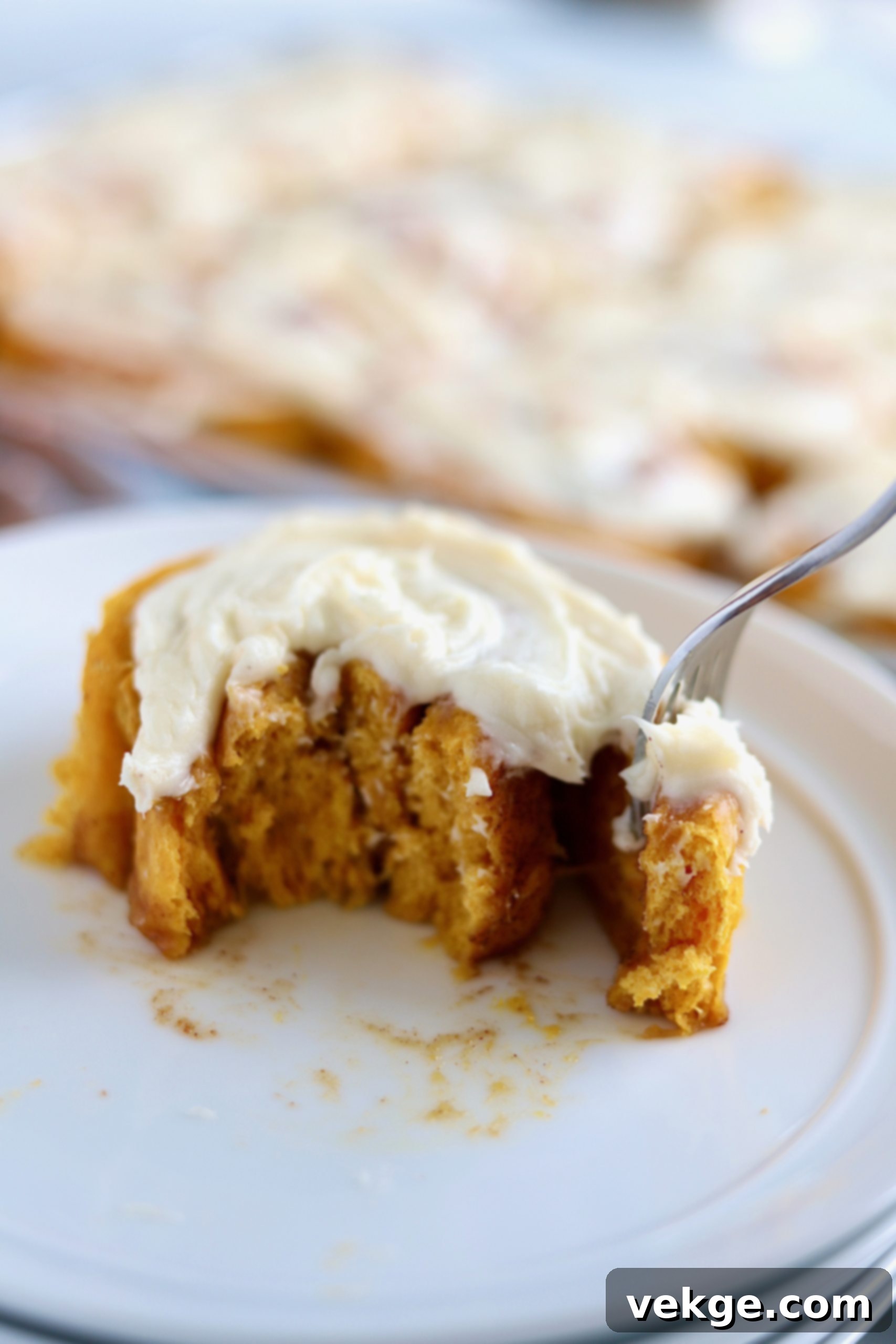 Pumpkin Cinnamon Rolls 3 A close-up shot of freshly baked pumpkin cinnamon rolls with a thick layer of cream cheese frosting.