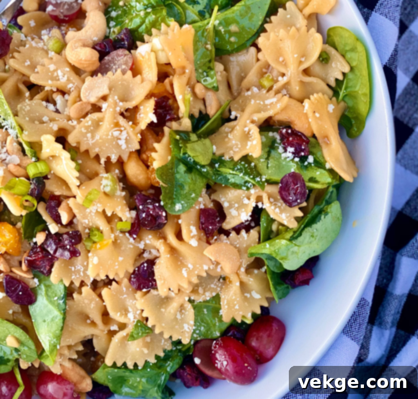 Zesty Pasta Toss 4 Close-up of a vibrant Pasta Salad with bow ties, spinach, and oranges.