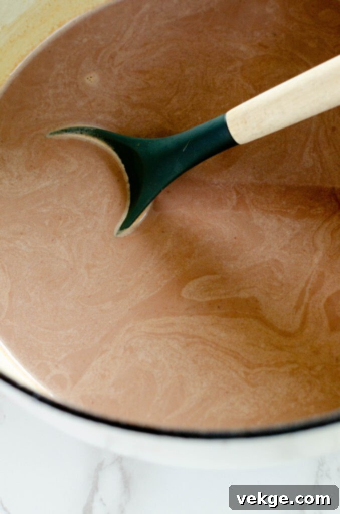 A measuring spoon filled with unsweetened cocoa powder, ready to be added to the pot.