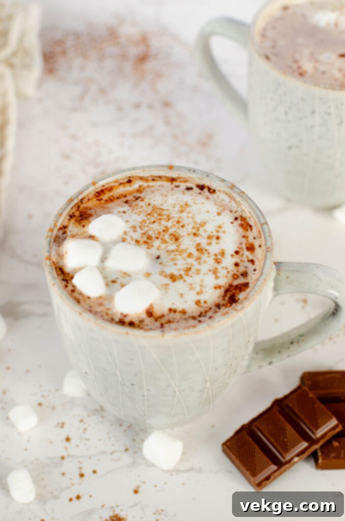 A jug of pure maple syrup next to a bowl of cocoa powder, ingredients for homemade hot chocolate.