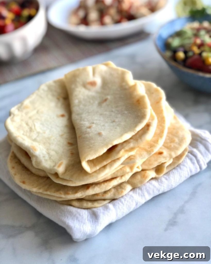 Freshly made homemade flour tortillas stacked on a cutting board, ready to be served.