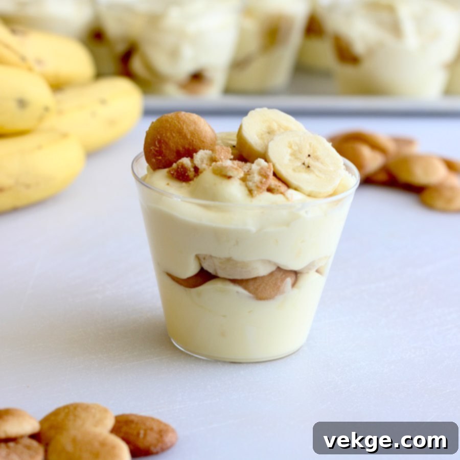 Close-up of a single banana pudding cup showing layers of cookies, bananas, and pudding