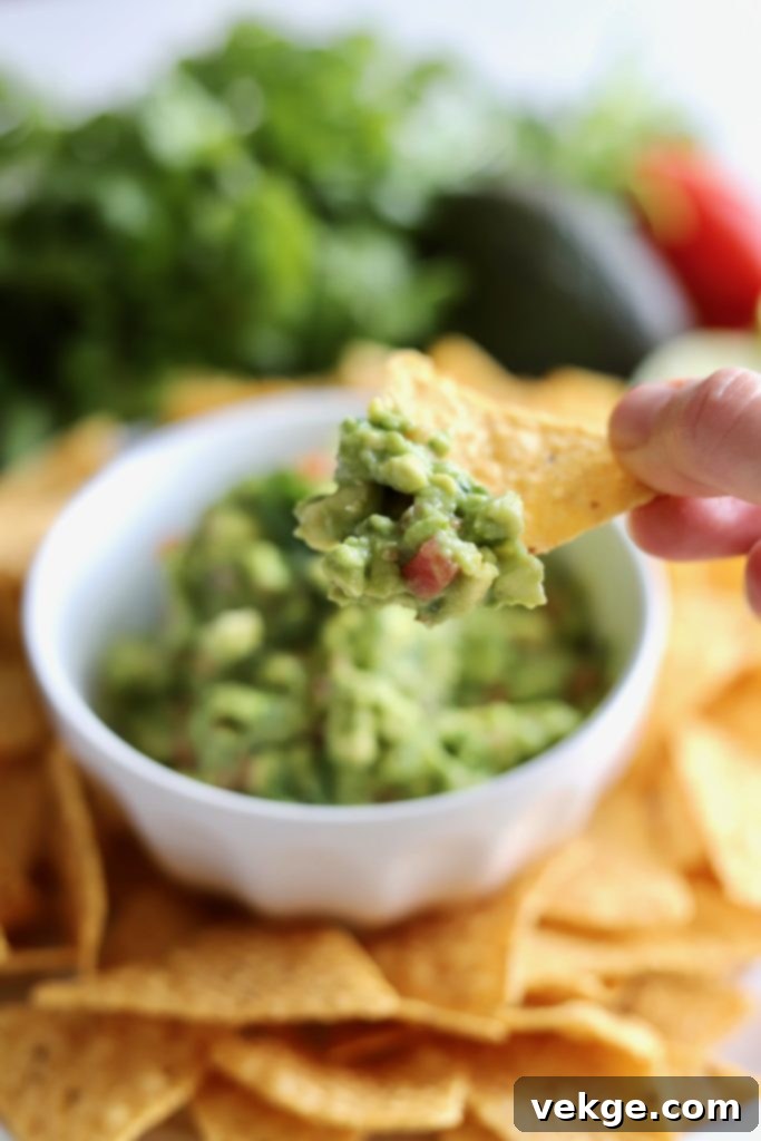 Bowl of homemade guacamole and a tortilla chip with guacamole on it
