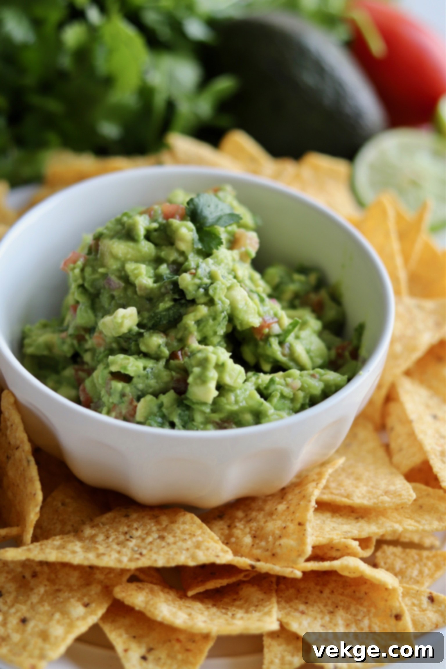 bowl of homemade green guacamole surrounded by tortilla chips