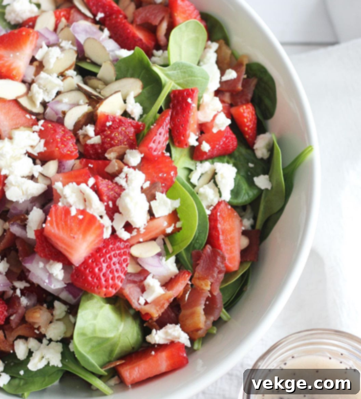 Refreshing Poppy Seed Salad 4 A small bowl of creamy homemade poppy seed dressing with a spoon, accompanied by fresh spinach leaves, highlighting the dressing's texture and the poppy seeds within.