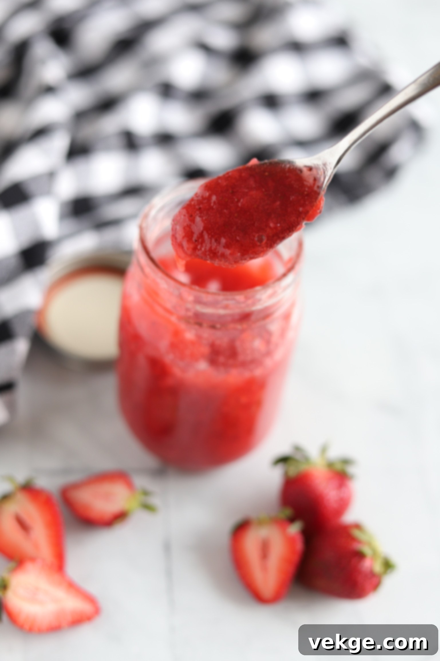 Effortless Strawberry Bliss Freezer Jam 7 A bowl of creamy yogurt topped with a swirl of red strawberry jam and fresh berries.