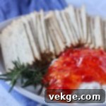 Sweet Heat Cheese Board 3 Close-up of a jar of sweet-and-hot red pepper jelly, highlighting its rich color and texture.