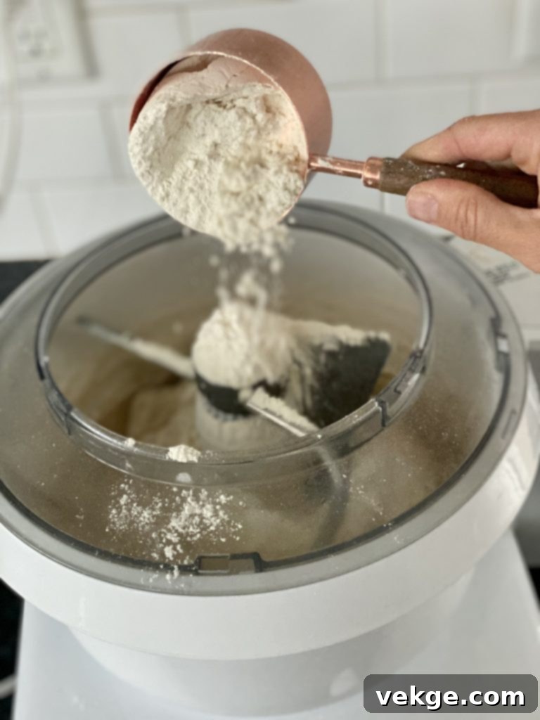 Effortlessly Divine Cinnamon Rolls 5 Close-up of dough being kneaded in a stand mixer, with flour visible on the sides of the bowl.