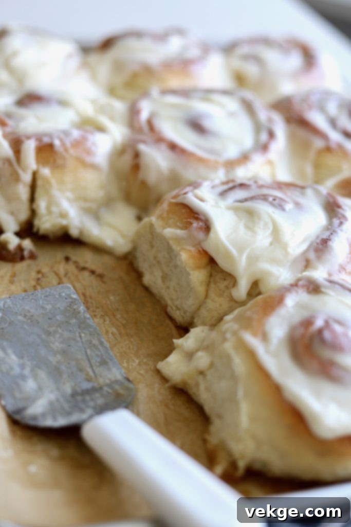 A close-up of a beautifully frosted sourdough cinnamon roll.