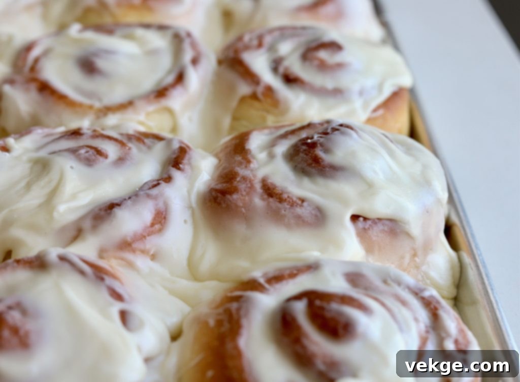 Close-up of fluffy, golden-brown sourdough cinnamon rolls cooling on a wire rack.