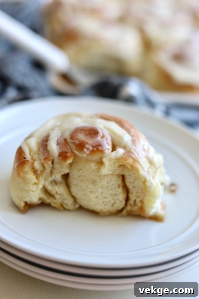 A close-up of a perfectly baked sourdough cinnamon roll, showing its soft, swirled interior.