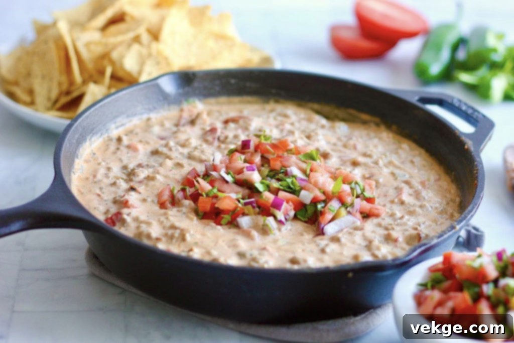 Ultimate Sausage Queso 2 Sizzling skillet of savory Sausage Queso, garnished with fresh pico de gallo, ready for dipping.