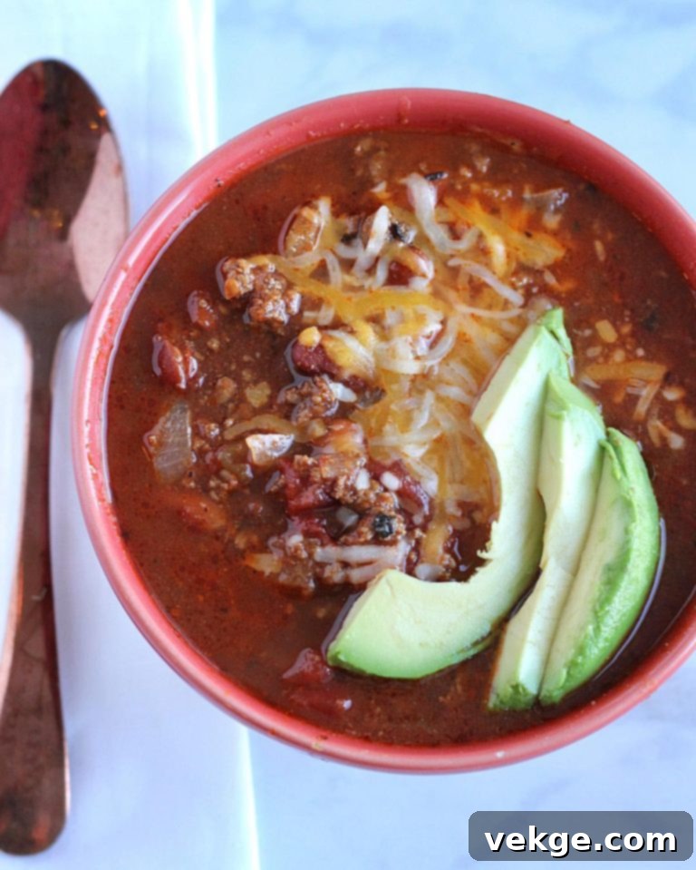 Rich, homemade chili with a spoon, showing texture and depth of color.