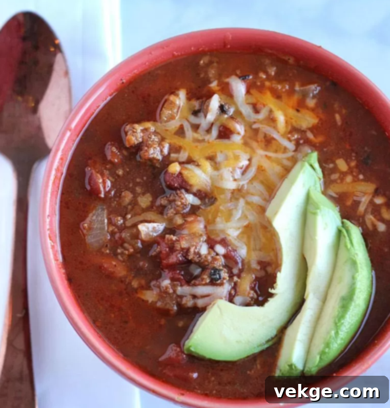 A bowl of delicious chili topped with sour cream, cheese, and fresh herbs.
