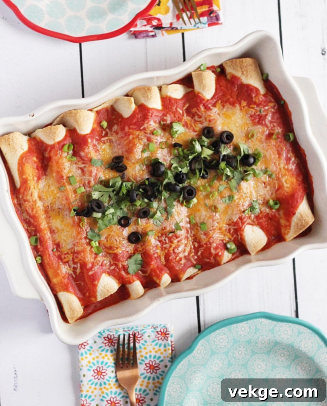 Savory Black Bean and Spinach Enchiladas 4 A single serving of black bean and spinach enchiladas on a white plate, topped with a dollop of sour cream or crema and fresh cilantro.