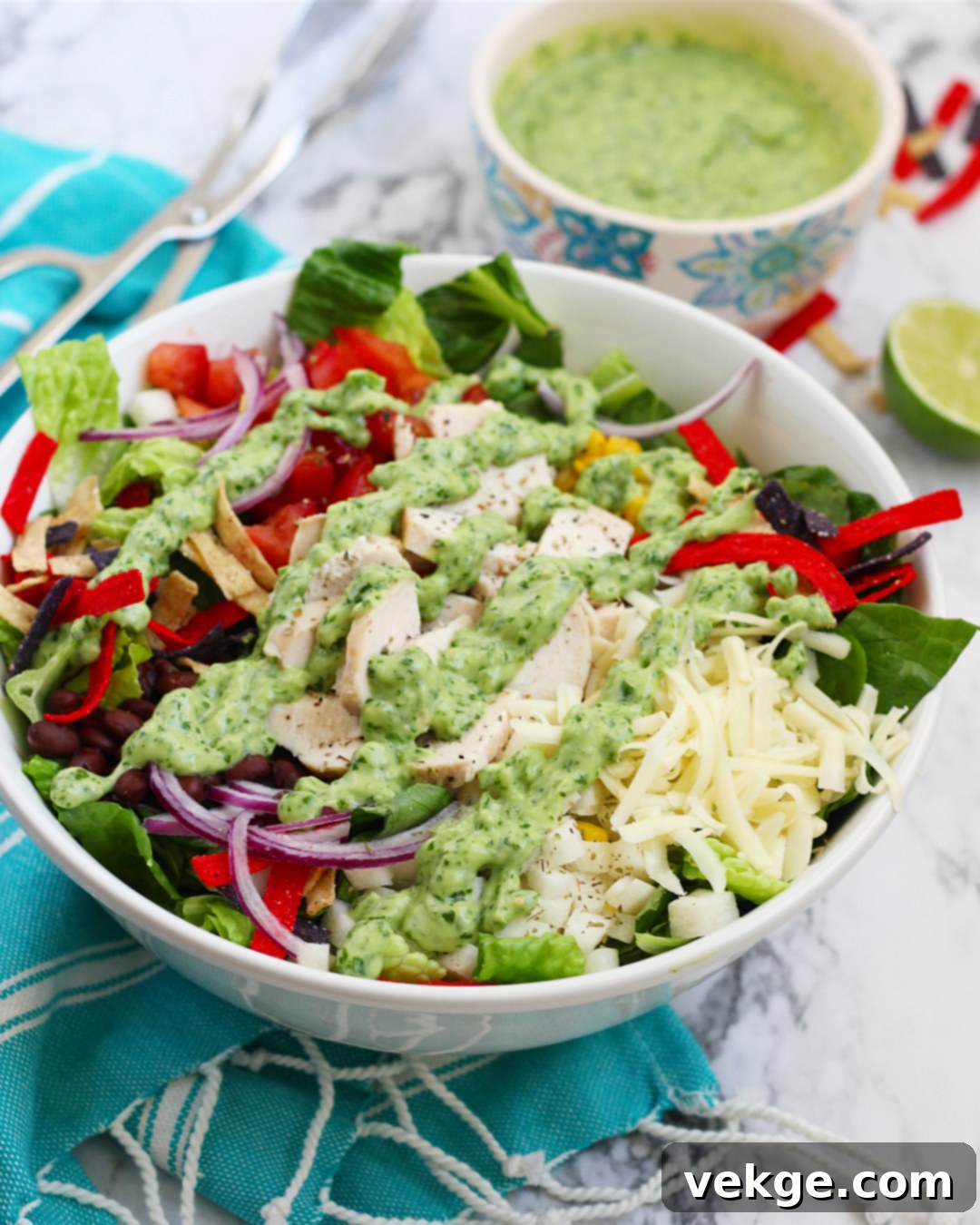 Vibrant Southwest Chicken Salad with creamy avocado dressing on a rustic wooden board, garnished with fresh cilantro and lime.
